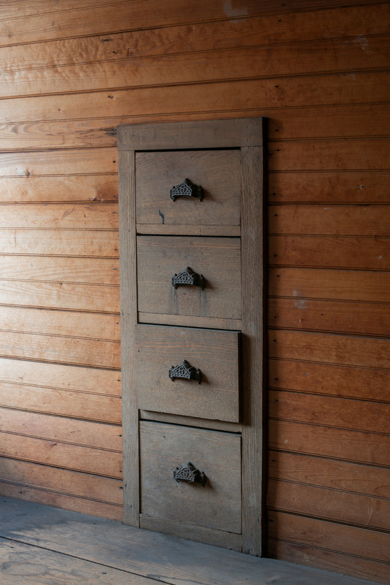 Three wooden built-in drawers with pulls on a paneled wood wall.