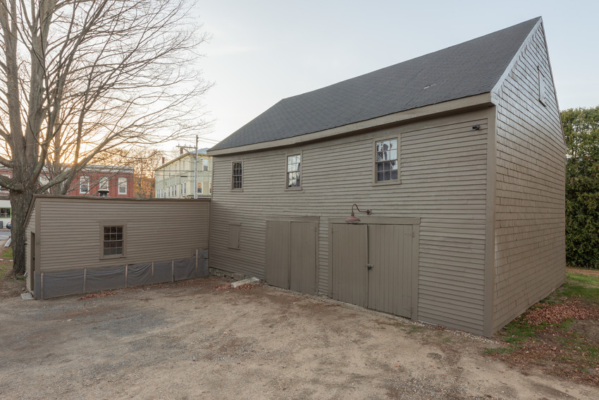 A brown barn with two double wide doors and a small ell on the left.