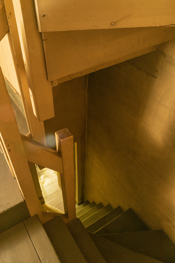 A wooden stairwell, painted a light yellow.