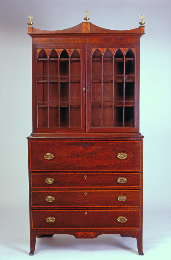 A large wooden secretary desk with glass doors on the top half, brass finials and handles.